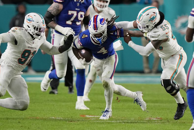 El defensive end de los Dolphins de Miami Emmanuel Ogbah y el linebacker Jerome Baker intentan derribar al corredor de los Bills de Búfalo James Cook en el encuentro del domingo 7 de enero del 2024. (AP Foto/Wilfredo Lee)
