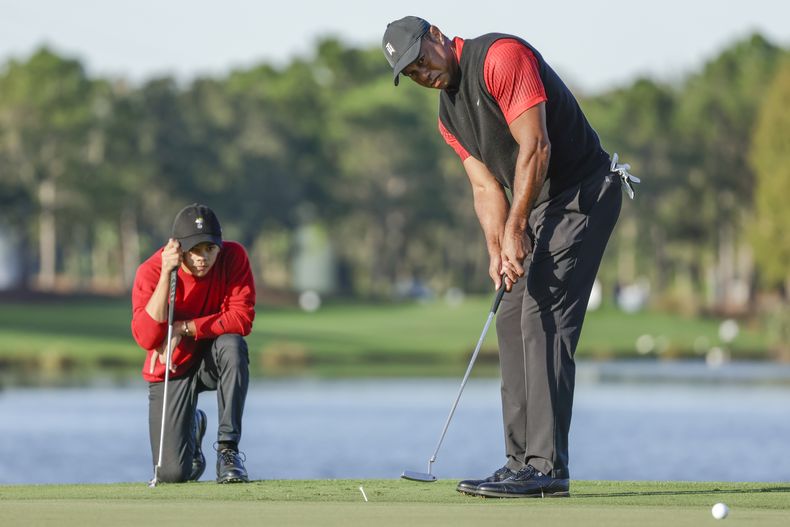 Bajo la mirada de su hijo Charlie (izquierda), Tiger Woods observa su golpe en el Campeonato PNC, el 18 de diciembre de 2022, en Orlando, Florida (AP Foto/Kevin Kolczynski)