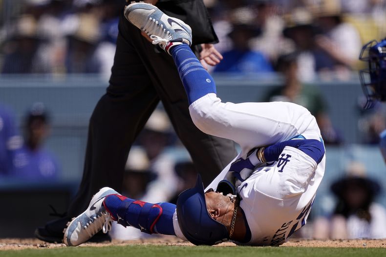 Mookie Betts, de los Dodgers de Los Ángeles (izquierda), se retuerce de dolor sobre el terreno tras ser golpeado por un lanzamiento, durante la séptima entrada del juego ante los Reales de Kansas City, el 16 de junio de 2024, en Los Ángeles. (AP Foto/Mark J. Terrill)