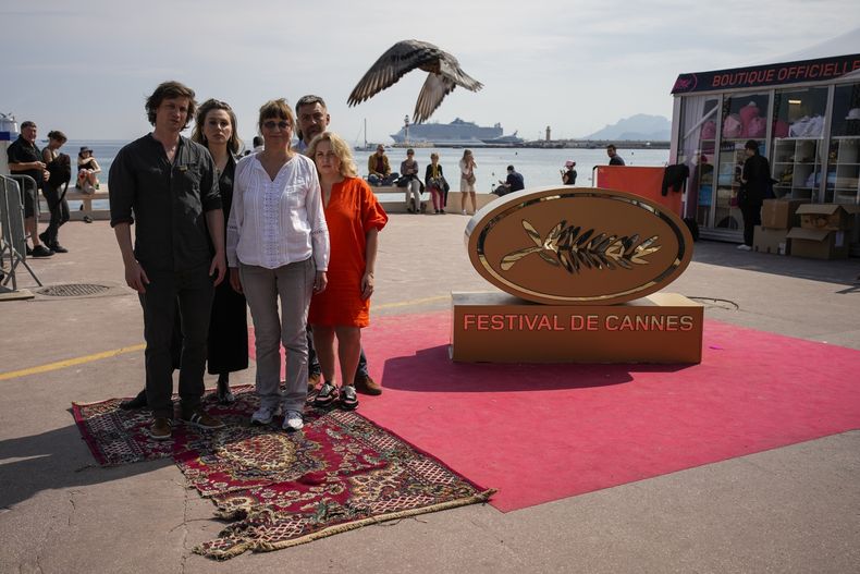 El equipo del documental In the Rearview, Maciek Hamela, de izquierda a derecha, Kseniia Marchenko, Larysa Sosnovtseva, Yura Dunay y Anna Palenchuk en una alfombra originalmente dañada por una bomba en la ciudad de Lukashivka en Ucrania posa en el Boulevard de la Croisette en la 76a edición del Festival de Cine de Cannes en Cannes, en el sur de Francia, el 21 de mayo de 2023. (Foto AP/Daniel Cole)