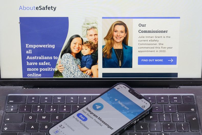 Un celular se ve sobre una computadora que muestra el sitio web australiano eSafety en Sydney, el jueves 30 de julio de 2026. (AP Foto/Rick Rycroft)
