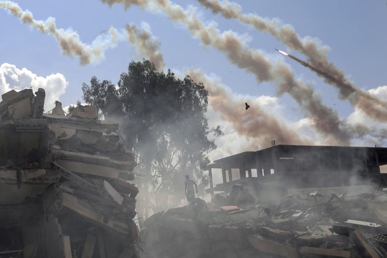 Proyectiles disparados desde la Franja de Gaza hacia Israel pasan sobre edificio destruidos por los ataques aéreos israelíes sobre la Ciudad de Gaza, en el centro del enclave palestino, el 19 de octubre de 2023. (AP Foto/Mohammed Dahman)