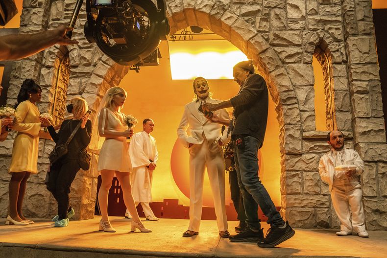 En esta imagen proporcionada por Warner Bros. Pictures los actores Lady Gaga, izquierda, y Joaquin Phoenix, centro, en el set con el cineasta Todd Phillips durante el rodaje de Joker: Folie à Deux. (Niko Tavernise/Warner Bros. Pictures vía AP)