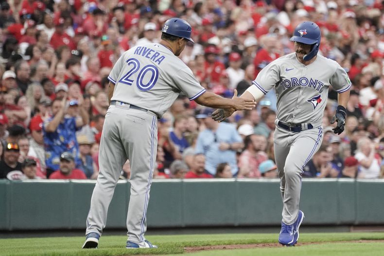 Davis Schneider, de los Azulejos de Toronto, festeja con el coach de tercera Luis Rivera luego de conectar un jonrón en el juego del sábado 19 de agosto de 2023, ante los Rojos de Cincinnati (AP Foto/Joshua A. Bickel)