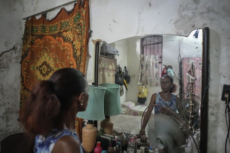 Maricelys Colás posa para la foto en un espejo en su habitación dentro de una mansión deteriorada en la que vive con otras cinco familias en la calle Villegas de La Habana, Cuba, el jueves 5 de octubre de 2023. "¿Cómo no vamos a vivir con miedo? Cada vez que llueve siento cómo las piedras me caen", dijo la mujer jubilada de 64 años que ha vivido en la casa por más de 59 años con su madre de 85. (AP Foto/Ramón Espinosa)