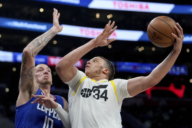 Kenneth Lofton Jr., del Jazz de Utah, salta hacia la cesta frente a Daniel Theis, de los Clippers de Los Ángeles, el viernes 12 de abril de 2024 (AP Foto/Eric Thayer)