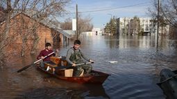 Dos hombres se desplazan en un bote en el que llevan alimentos en un área inundada, el jueves 11 de abril de 2024, en Orenburg, Rusia. (AP Foto)