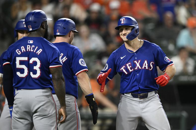 Wyatt Langford, derecha, de los Rangers de Texas, celebra su cuadrangular de tres carreras con Adolis García (53) y Robbie Grossman, centro, durante la octava entrada del juego de béisbol en contra de los Orioles de Baltimore, el domingo 30 de junio de 2024, en Baltimore. El jonrón completó el ciclo para Langford. Los Rangers ganaron 11-2. (AP Foto/Nick Wass)