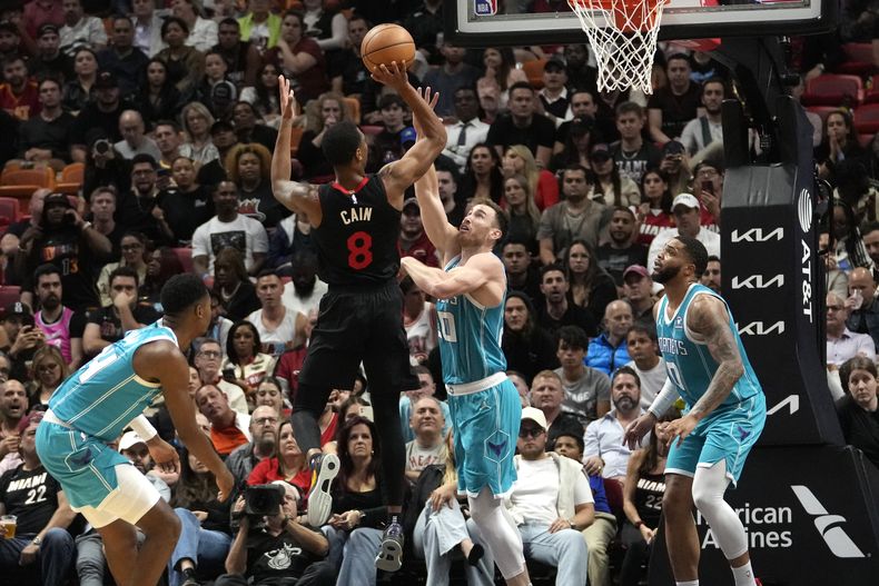 Jamal Cain (8), del Heat de Miami, dispara sobre Gordon Hayward (20), de los Hornets de Charlotte, durante la segunda mitad del juego de baloncesto de la NBA, el miércoles 13 de diciembre de 2023, en Miami. (AP Foto/Lynne Sladky)