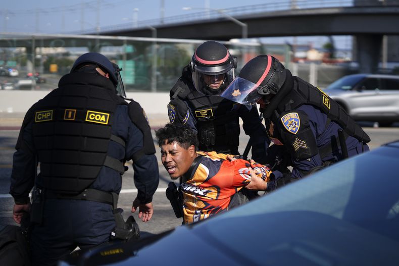 Un manifestante es arrestado por agentes de la Patrulla de Caminos de California cerca del edificio federal en el centro de Los Ángeles el martes 10 de junio de 2025. (AP Foto/Eric Thayer)
