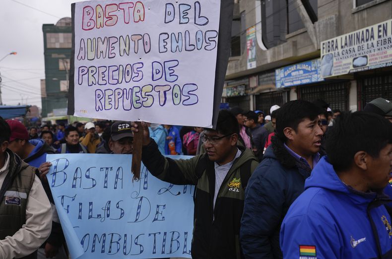 Un conductor de transporte público sostiene un cartel durante una protesta pidiendo un aumento de tarifas en medio de fuertes aumentos en el costo de vida en El Alto, Bolivia, el miércoles 4 de diciembre de 2024. (AP Foto/Juan Karita)