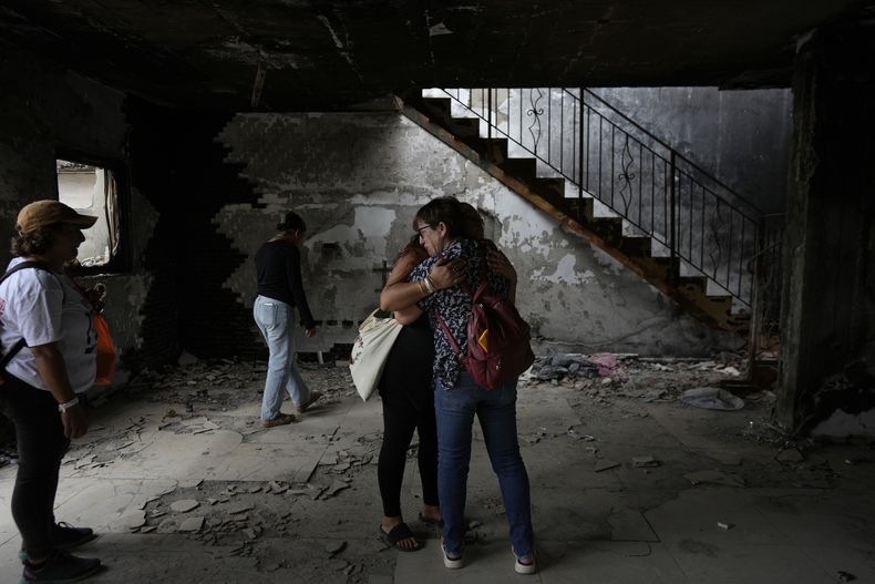 Gente abrazada en la casa de Maayan y Yuval Bar, asesinados por Hamás, en el primer aniversario del ataque de Hamás a Israel, en el kibutz Beeri, una granja comunal israelí en la frontera con Gaza, el lunes 7 de octubre de 2024. (AP Foto/Ohad Zwigenberg)