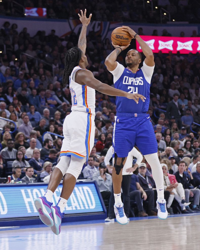 El escolta de los Clippers de Los Ángeles, Norman Powell, a la derecha, se prepara para disparar contra el escolta del Thunder de Oklahoma City, Cason Wallace, a la izquierda, durante la segunda mitad de un partido de baloncesto de la NBA, el jueves 22 de febrero de 2024, en Oklahoma City. (AP Foto/Nate Billings)