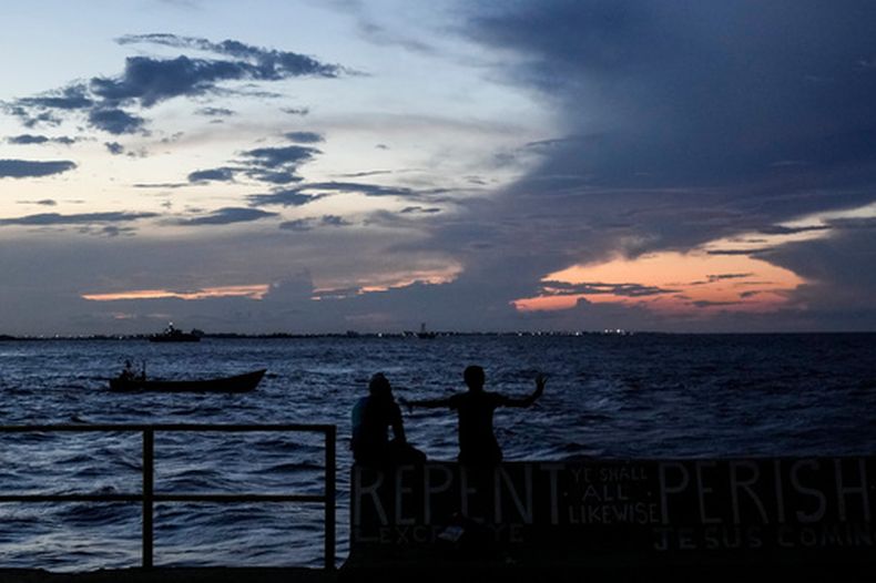 ARCHIVO - Gente sentada en un muelle al atardecer en Georgetown, Guyana, el martes 19 de noviembre de 2024. (AP Foto/Matias Delacroix, Archivo)