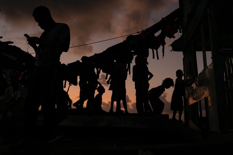 Migrantes se relajan al atardecer en la isla de Gardi Sugdub, en la costa caribeña de Panamá, el 23 de febrero de 2025, donde pasaron la noche antes de intentar tomar barcos hacia Colombia, un día después de regresar desde el sur de México, tras abandonar sus esperanzas de llegar a Estados Unidos debido a la campaña antiinmigración del presidente Donald Trump. (AP Foto/Matias Delacroix)
