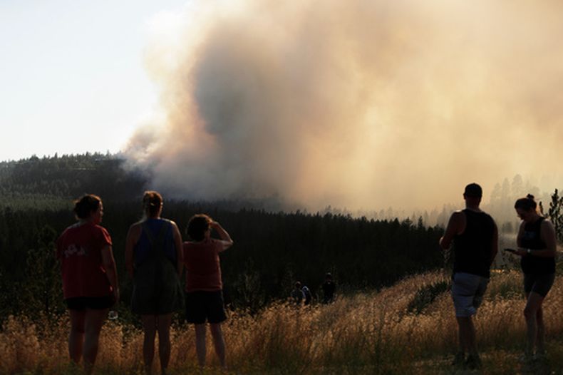Gente mira el incendio de Old Trails desde el W. Northwest Boulevard, el sábado 1 de agosto de 2026, en Spokane, Washington. (AP Foto/Young Kwak)