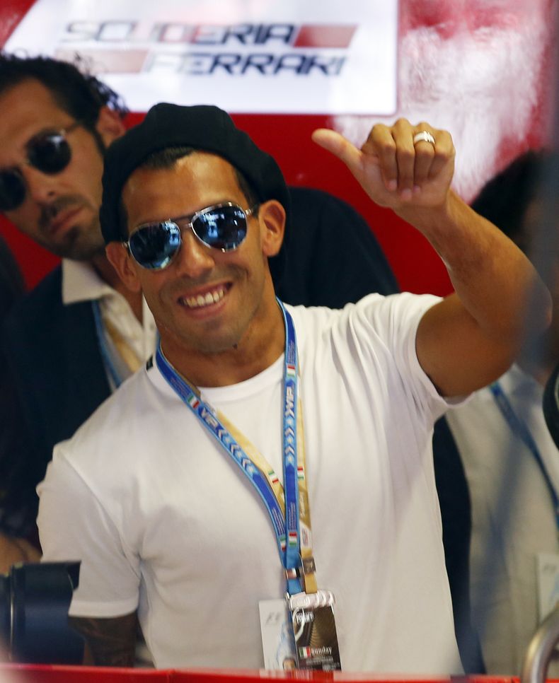 El jugador de la Juventus, Carlos Tevez, saluda desde los pits de Ferrari en el GP de Italia el domingo, 7 de septiembre de 2014, en Monza. (AP Photo/Luca Bruno)
