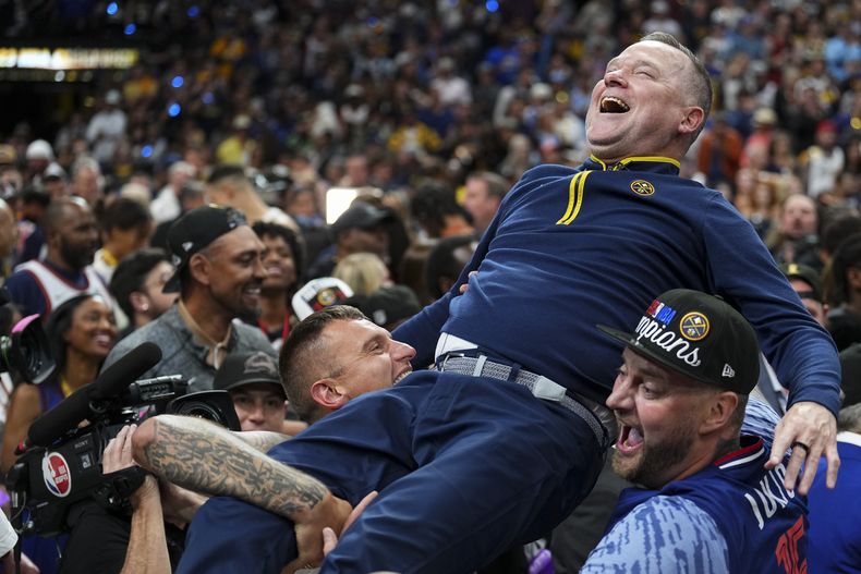 Michael Malone, entrenador de los Nuggets de Denver, es levantado por un grupo de fanáticos tras coronarse en las Finales de la NBA ante el Heat de Miami, el lunes 12 de junio de 2023