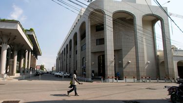 ARCHIVO - Un peatón camina cerca del Banco de la República de Haití, a la derecha, el jueves 21 de marzo de 2019, en Puerto Príncipe, Haití. (AP Foto/Dieu Nalio Chery, archivo)