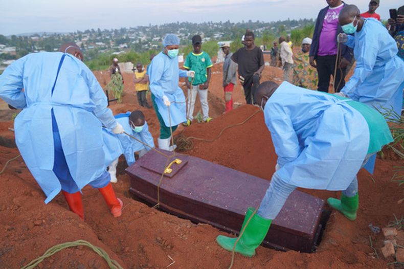 Varias personas con equipos de protección colocan un ataúd con los restos de Baudjo Baraka Jules, de 6 años y que murió de ébola, en una tumba, en Bunia, en la provincia de Ituri, República Democrática del Congo, el 18 de agosto de 2026. (AP Foto/Dieudonne Dirole)