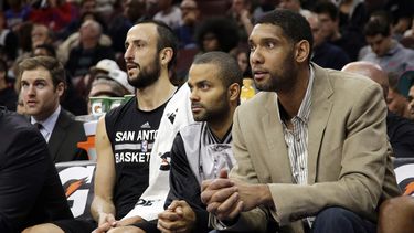 americateve | Tim Duncan, desde la derecha, Tony Parker y Manu Gin&oacute;bili observan desde la banca de los Spurs de San Antonio el partido ante los 76ers de Filadelfia, el lunes 1 de diciembre de 2014. (AP Foto/Matt Slocum)