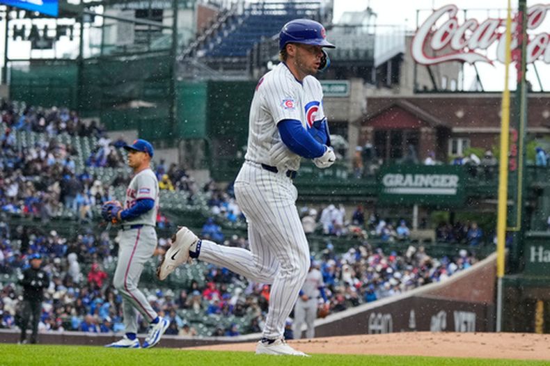 Nico Hoerner, de los Cachorros de Chicago, en primer plano, camina hacia la primera base durante la primera entrada de un juego de béisbol contra los Mets de Nueva York en Chicago, el domingo 19 de abril de 2026. (AP Foto/Nam Y. Huh)