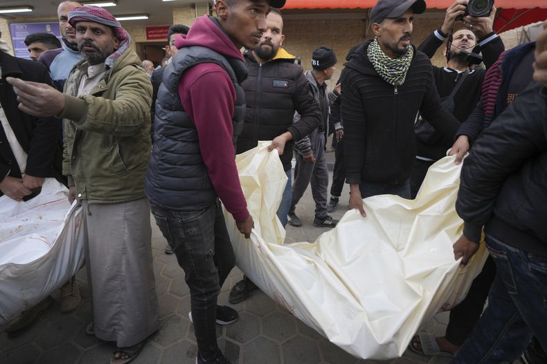 Palestinos trasladan sacos blancos con los cuerpos de los fallecidos en ataques aéreos nocturnos israelíes en el campo de refugiados de Maghazi, en el hospital Al-Aqsa, en Deir al-Balah, en el centro de Gaza, el 28 de diciembre de 2024. (AP Foto/Abdel Kareem Hana)