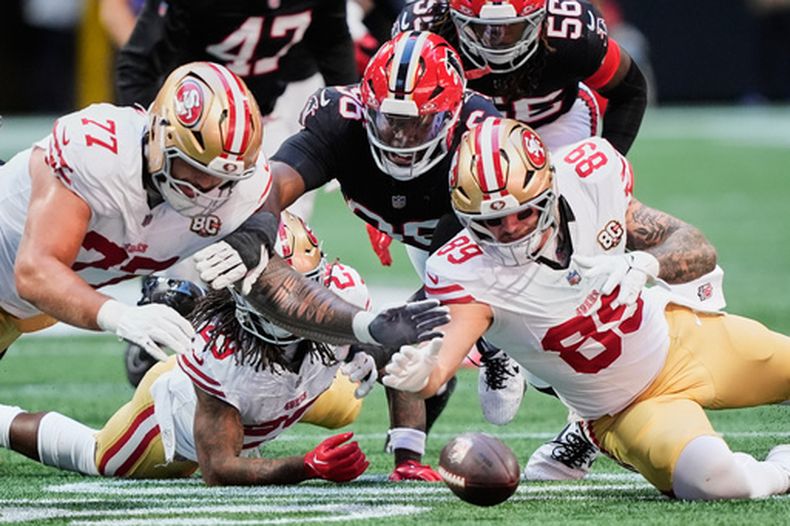 Dominick Puni (77), Luke Farrell (89), de los 49ers de San Francisco y Gervon Dexter Sr., centro, de los Falcons de Atlanta, se lanzan para tratar de tomar un balón suelto de Jordan James, corredor de los 49ers, durante la primera mitad del partido de la NFL, el domingo 25 de octubre de 2026, en Atlanta. (AP Foto/Brynn Anderson)