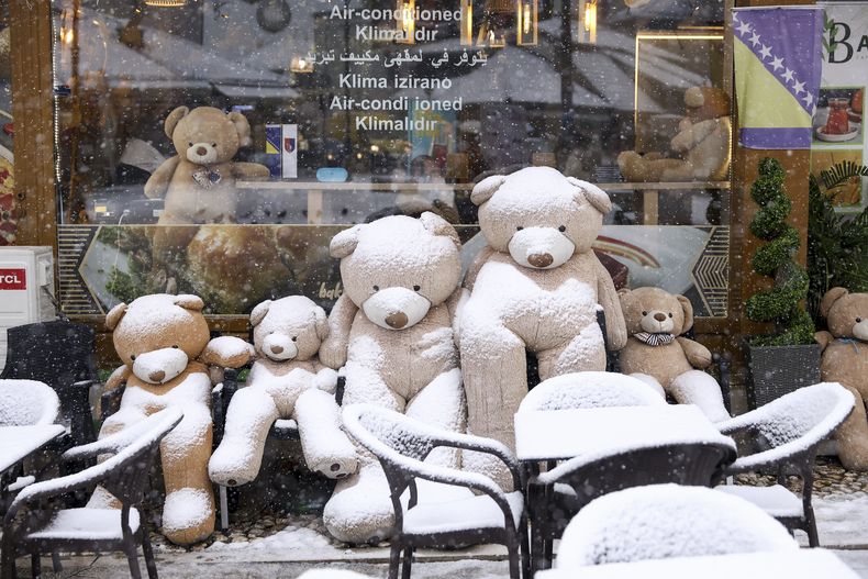 Osos de peluche cubiertos de nieve afuera de una cafetería en el centro de Sarajevo, Bosnia, el 23 de diciembre de 2024. (AP Foto/Armin Durgut)