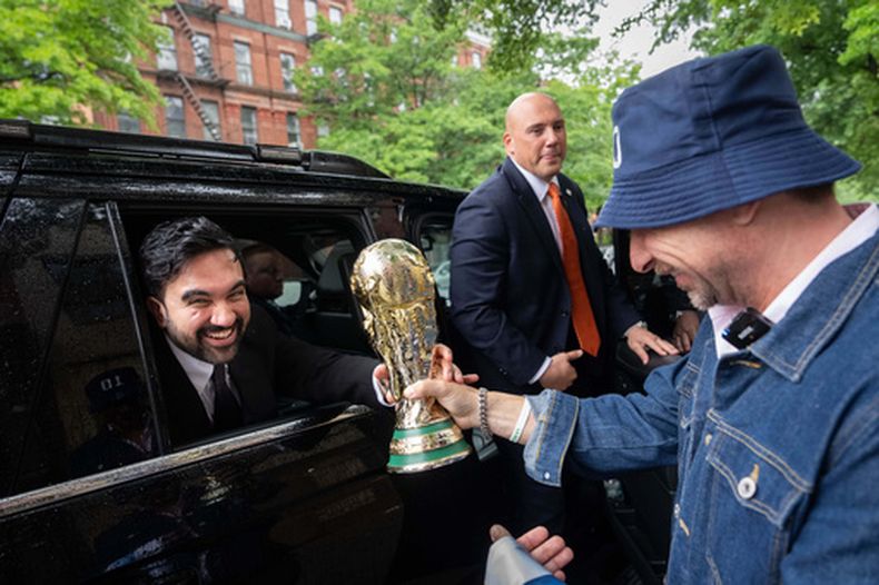 El alcalde de Nueva York Zohran Mamdani recibe una réplica de la Copa del Mundo por parte de Ezequiel Cecchi, de 49 años, tras un anuncio relacionado sobre el Mundial, el jueves 21 de mayo de 2026, en Nueva York. (AP Foto/Adam Gray)