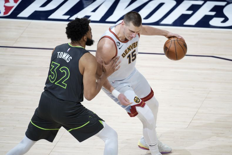 El jugador de los Nuggets de Denver Nikola Jokic, a la derecha, trata de eludir al jugador de los Timberwolves de Minnesota Karl-Anthony Towns en la primera mitad del quinto partido de su serie de primera ronda de playoffs de la NBA, el martes 25 de abril de 2023 en Denver. (AP Foto/David Zalubowski)