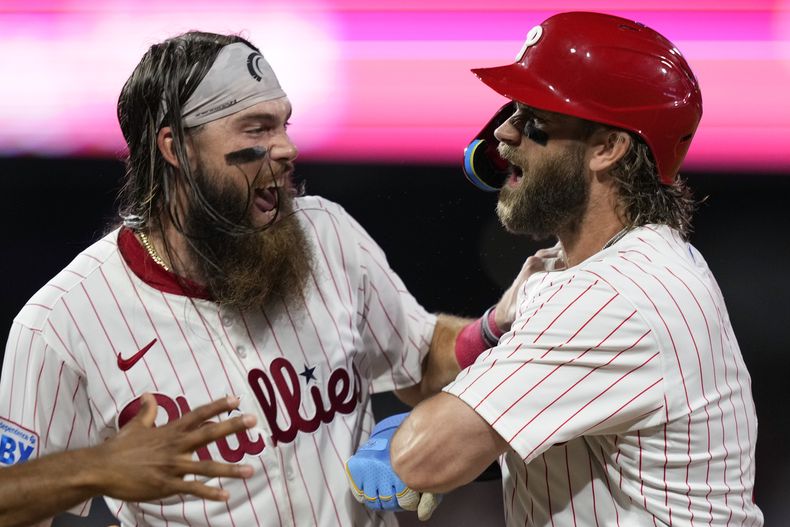 Bryce Harper (derecha) y Brandon Marsh de los Filis de Filadelfia, celebran el hit ganador de Harper ante el lanzador de los Astros de Houston, Josh Hader durante el 10mo episodio del juego de béisbol, el lunes 26 de agosto de 2024, en Filadelfia. (AP Foto/Matt Slocum)