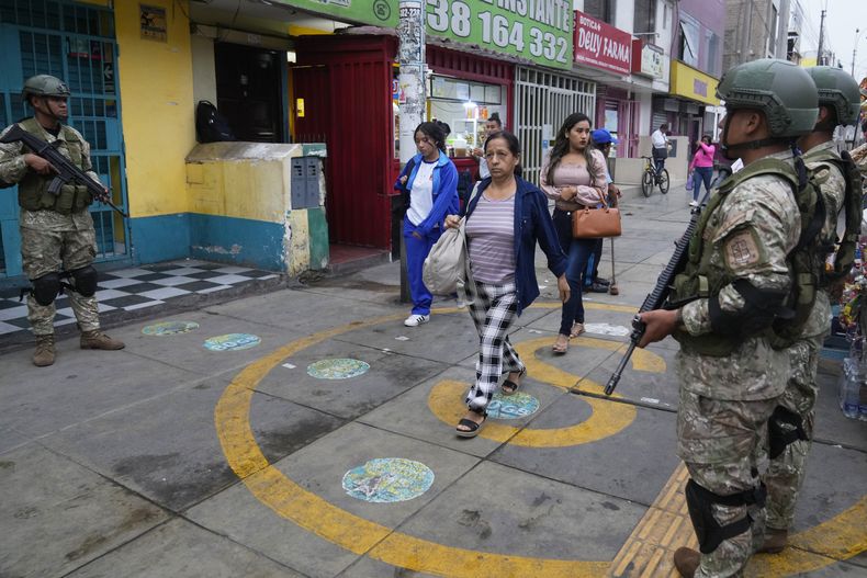 Peatones pasan junto a soldados en Lima, Perú, el miércoles 19 de marzo de 2025, después de que la presidenta Dina Boluarte declarara el estado de emergencia y desplegara tropas para ayudar a la policía a combatir un repunte de violencia. (Foto AP/Martín Mejía)