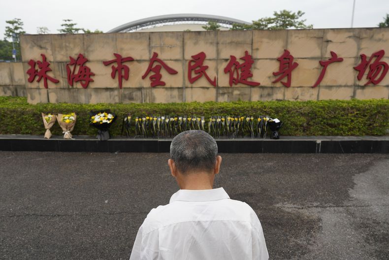 Un hombre de pie el miércoles 13 de noviembre de 2024 cerca de un sitio de homenaje improvisado afuera de una plaza de Zhuhai, en la provincia de Guangdong, en el sur de China, donde un hombre embistió a una multitud que se ejercitaba en el centro deportivo. (AP Foto/Ng Han Guan, Archivo)