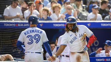 El dominicano Vladimir Guerrero Jr. (derecha), de los Azulejos de Toronto, festeja con su compañero Kevin Kiermaier, quien anotó ante los Bravos de Atlanta el sábado 13 de mayo de 2023 (Christopher Katsarov/The Canadian Press via AP)