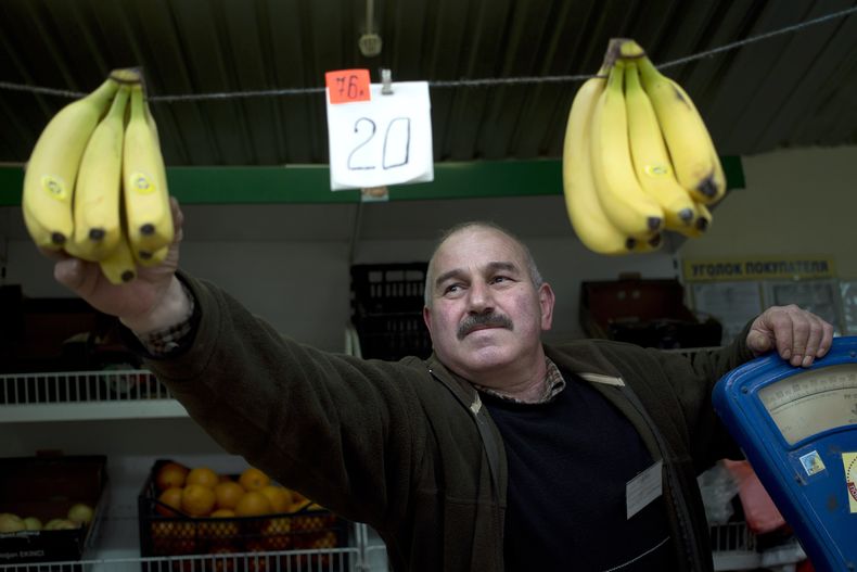 Un vendedor ambulante cuelga bananas con el precio en rulos y hryvnias en Simferopol, Crimea, el mi&eacute;rcoles, 26 de marzo del 2014. (Foto AP/Pavel Golovkin)