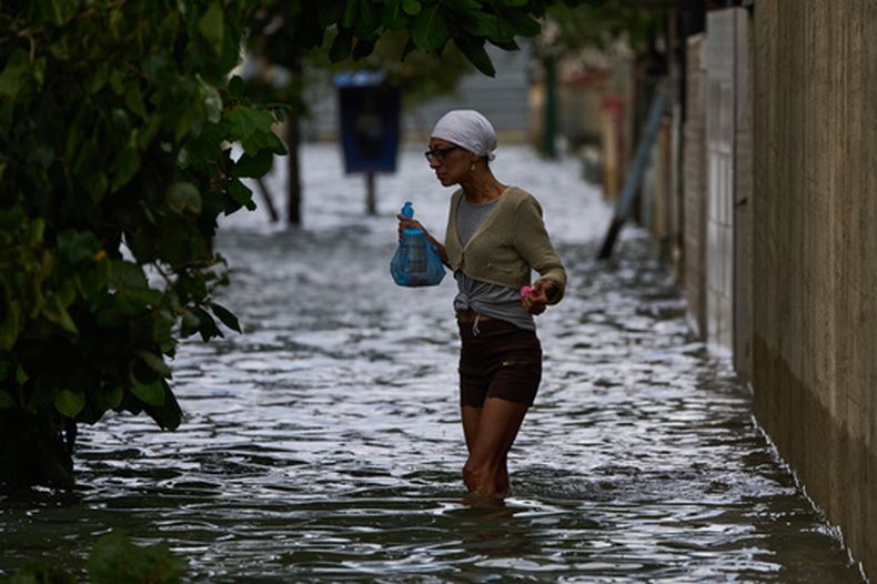 Una mujer camina por una calle inundada el domingo 1 de febrero de 2026, en La Habana. (AP Foto/Ramón Espinosa)