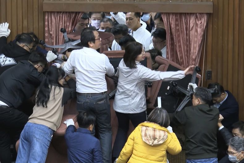 En esta imagen, tomada de un video de EBC Taiwán, legisladores del Partido Progresista Democrático utilizan sillas para bloquear la entrada de miembros del Partido Nacionalista, o Kuomintang, que tratan de irrumpir en la cámarada, en Taipéi, Taiwán, el 20 de diciembre de 2024. (EBC vía AP)