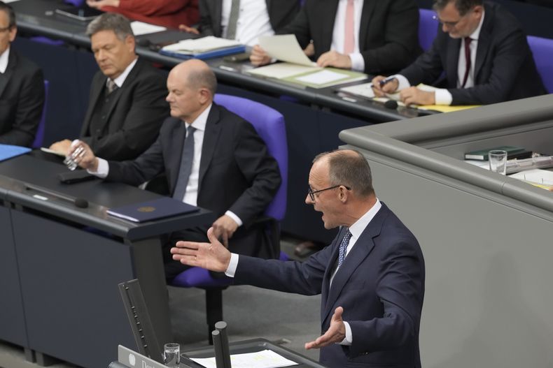 El líder opositor, Friedrich Merz, derecha, de CDU, habla mientras el canciller alemán, Olaf Scholz, centro, observa, en una sesión plenaria en el Bundestag o Parlamento alemán, donde enfrenta un voto de censura, en Berlín, Alemania, el lunes 16 de diciembre de 2024. (AP Foto/Markus Schreiber)