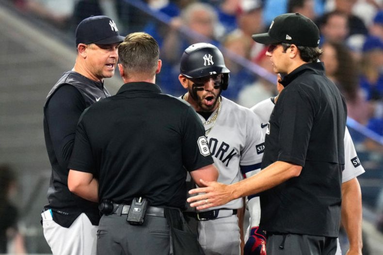 José Caballero (tercero desde la izquierda), de los Yankees de Nueva York, y el mánager Aaron Boone (izquierda) intercambian puntos de vista con el umpire de home Steven Jaschinski (segundo desde la izquierda) y el umpire de segunda base John Tumpane (al frente a la derecha) durante la sexta entrada de un partido de béisbol contra los Azulejos de Toronto en Toronto, el domingo 14 de junio de 2026. (Chris Young/The Canadian Press vía AP)