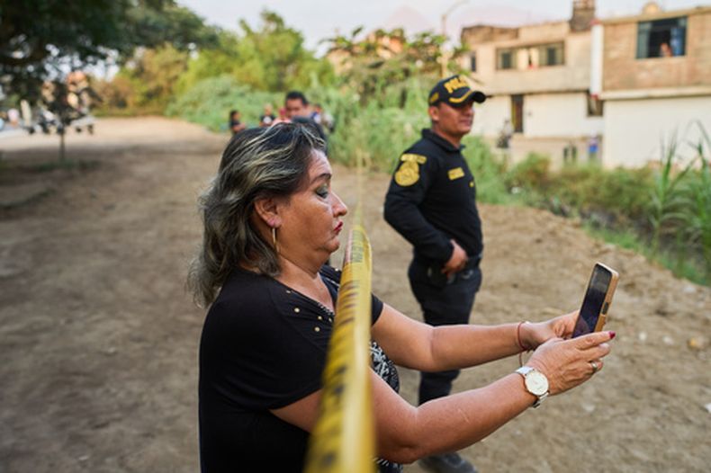 Una vecina graba la escena con su teléfono móvil mientras la policía recupera el cuerpo de José Pérez de un barranco donde fue hallado muerto a tiros en Trujillo, Perú, el viernes 30 de mayo de 2026. (AP Foto/Rodrigo Abd)