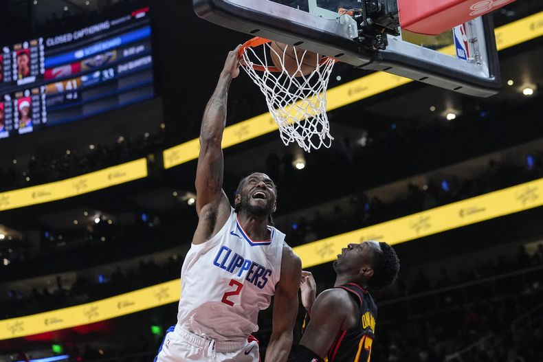 Kawhi Leonard (2), de los Clippers de Los Ángeles, encesta sobre la marca defensiva de Onyeka Okongwu (17), de los Hakws de Atlanta, durante la primera mitad del juego de baloncesto de la NBA, el lunes 5 de febrero de 2024, en Atlanta. (AP Foto/John Bazemore)