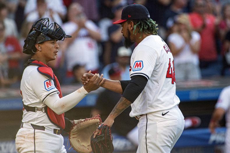 Bo Naylor, de los Guardianes de Cleveland, a la izquierda, felicita al cerrador Emmanuel Clase después del tercer out en la novena entrada contra los Gigantes de San Francisco en Cleveland, el sábado 6 de julio de 2024. (AP Foto/Phil Long)