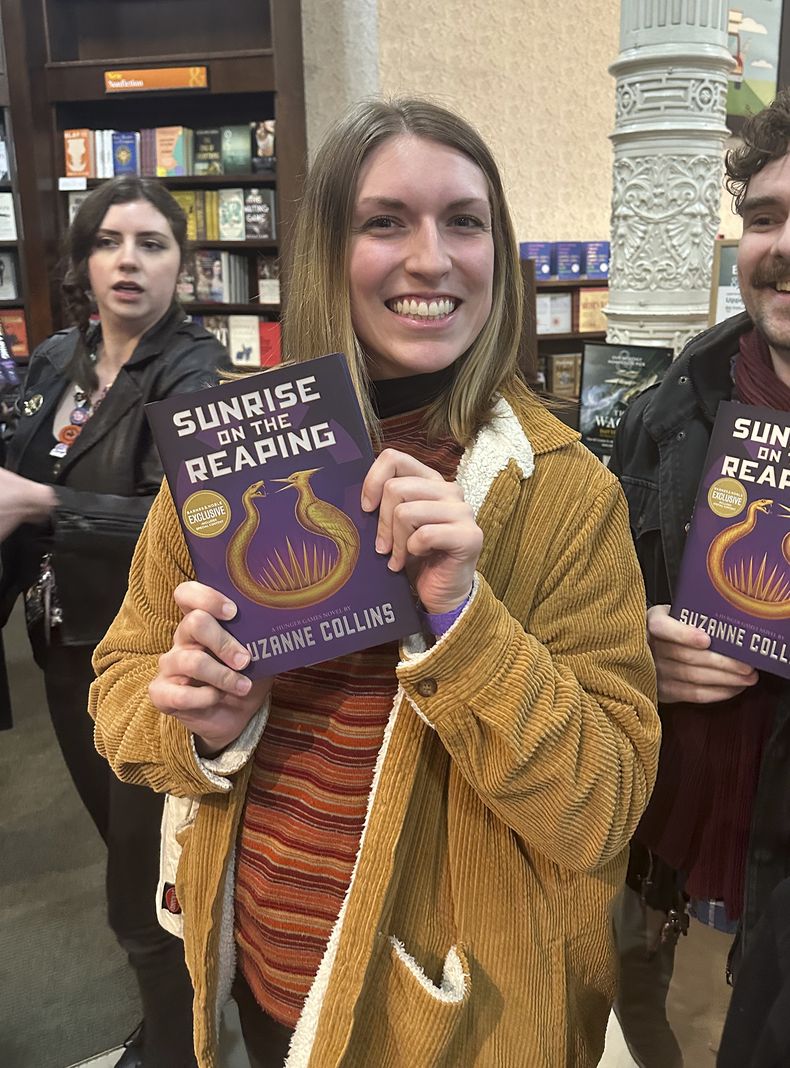 Savannah Miller sostiene su ejemplar de Sunrise on the Reaping de Suzanne Collins en una fiesta de lanzamiento de medianoche en la librería Barnes & Noble en Nueva York el martes 18 de marzo de 2025. (Foto AP/Hillel Italie)