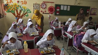 Estudiantes toman sus comidas durante la puesta en marcha del ambicioso programa de comidas gratuitas del presidente Prabowo Subianto para alimentar a los niños y las mujeres embarazadas en todo el país, a pesar de las críticas que dicen que su logística requerida podría dañar las finanzas estatales y la economía de Indonesia, en una escuela primaria en Depok, Java Occidental, Indonesia, lunes, 6 de enero de 2025. (AP foto/Dita Alangkara)