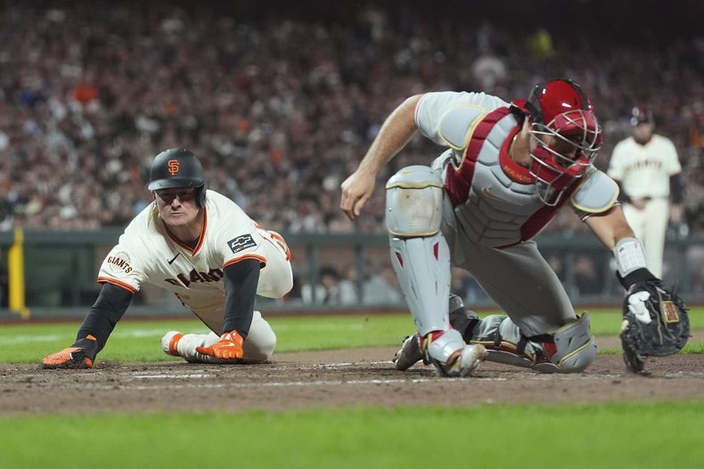 Matt Chapman, izquierda, de los Gigantes de San Francisco se barre de cabeza en el plato para anotar carrera frente a J.T. Realmuto, receptor de los Filis de Filadelfia durante la octava entrada del juego de béisbol de Grandes Ligas, el lunes 7 de julio de 2025, en San Francisco. (AP Foto/Jeff Chiu)