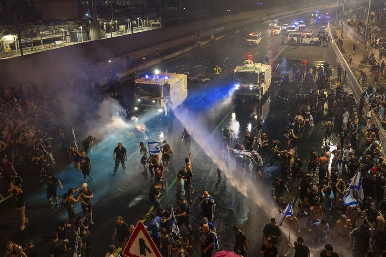 La policía antimotines intenta dispersar a manifestantes con un cañón hidrante durante una protesta contra el plan del gobierno de Benjamin Netanyahu de reformar el sistema judicial, en Tel Aviv, 24 de julio de 2023. (AP Foto/Oded Balilty)