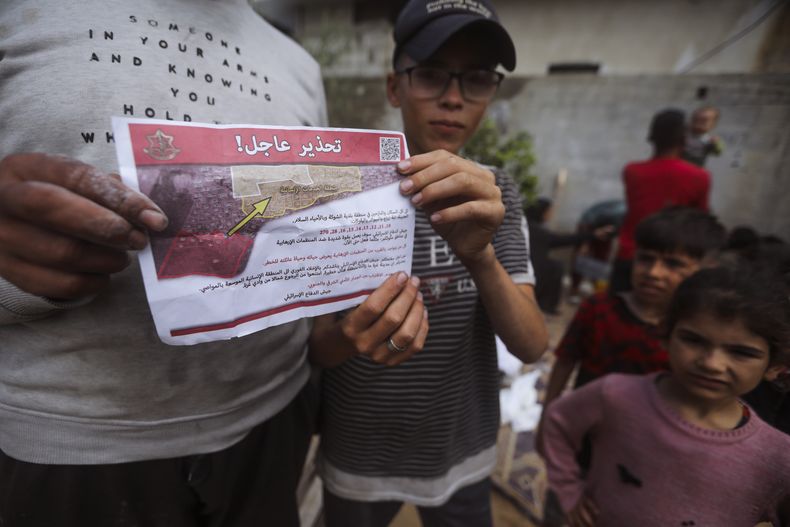 Palestinos sostienen folletos arrojados por aviones israelíes que les dicen que evacúen antes de una operación militar israelí en Rafah, en el sur de la Franja de Gaza, el lunes 6 de mayo de 2024. La orden afecta a decenas de miles de personas y podría apuntar a una invasión más amplia de la ciudad, que Israel ha identificado como el último bastión importante de Hamás tras siete meses de guerra. (AP Foto/Ismael Abu Dayyah)
