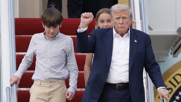 El presidente estadounidense Donald Trump alza un puño al bajar del Air Force One con sus nietos, Spencer y Chloe, a su llegada a la Base Conjunta Andrews, el 29 de julio de 2025, en Maryland. (AP Foto/Luis M. Alvarez)