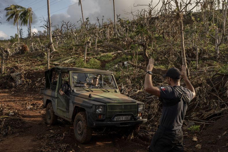 Agentes franceses de protección civil se abren paso a través de árboles destrozados en dirección a Mirereni, Mayotte, el viernes 20 de diciembre de 2024. (AP Foto/Adrienne Surprenant)